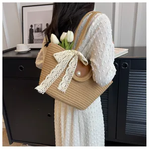 Détail du sac cabas tissé avec un nœud en dentelle blanche et un fermoir à perles chic