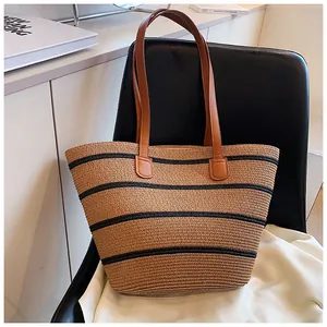 Close-up of striped straw tote bag with brown leather handles on a stylish chair