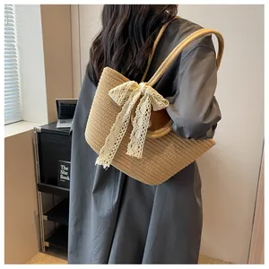 Détail du sac cabas en paille tressée avec nœud en dentelle blanche et anse ronde