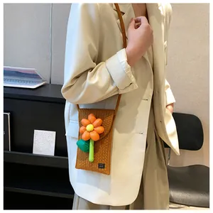 Modèle portant un sac de téléphone marron tissé main avec une fleur 3D orange