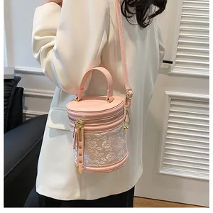 Close-up of pink bucket bag with white floral embroidery and gold-tone metal hardware
