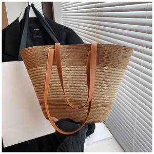 Detail of hand-woven straw tote with two-tone stitching and premium leather shoulder straps