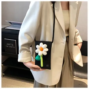 Détail d'un sac de téléphone noir tricoté avec applique marguerite et étiquette