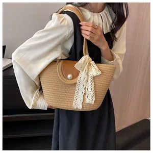 Détail du sac en paille avec rabat en cuir, bouton perle et nœud en dentelle