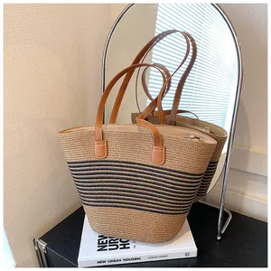 Detailed macro of the woven straw tote with black stripes and brown leather handles