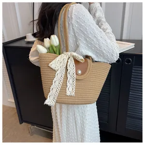 Détail du sac en paille avec nœud en dentelle blanche, rabat en cuir et perle fantaisie
