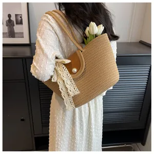 Détail du sac bandoulière en paille avec nœud en dentelle, perle et décor de tulipe
