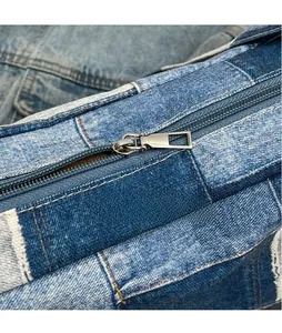 Detail eines silbernen Metallreißverschlusses an einer gewaschenen Denim-Umhängetasche