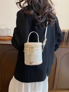 Elegant beige bucket bag with floral embroidery and gold zippers shown on model
