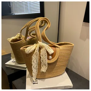 Détail du sac en paille avec nœud en dentelle blanche, perle et rabat en cuir