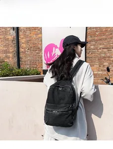 Dettaglio dello zaino in denim nero lavato con tasche a cerniera stratificate e spallacci