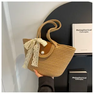 Détail du sac cabas tissé avec nœud en dentelle et rabat en cuir avec fermoir perle