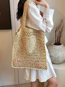 Handwoven beige straw tote bag with heart detail on a model in white dress