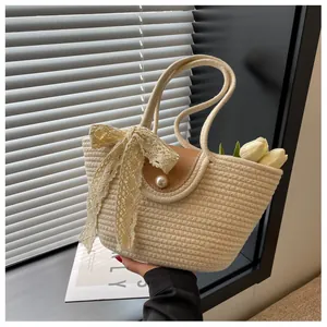 Détail du sac tressé avec nœud en dentelle, boucle en perle et rabat en cuir marron