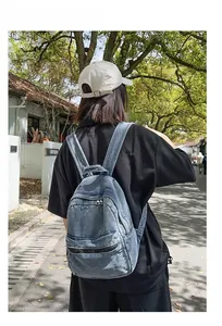 Dettaglio dello zaino in denim lavato vintage con tasca anteriore con cerniera e stile casual