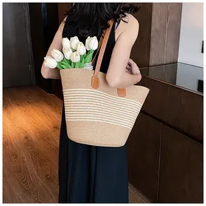 Close-up of the beige and white woven straw beach tote bag with premium brown leather straps
