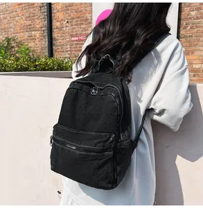 Dettaglio dello zaino in denim nero lavato con trama retrò e tasca anteriore zip