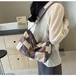 Modell trägt eine farbenfrohe Patchwork-Canvas-Hobo-Tasche in Braun, Beige und Schwarz