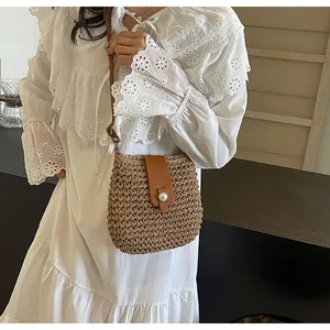 Detail van de geweven rieten crossbodytas met lederen flap en een grote parelknoop-sluiting