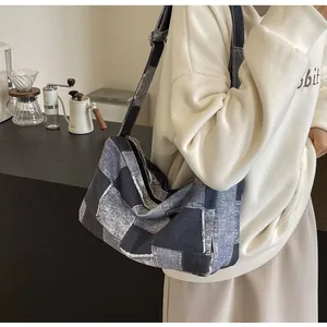 Detail einer großen gewaschenen Denim-Patchwork-Halbmondtasche mit breitem Schultergurt