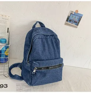 Dettaglio dello zaino in denim blu con tasca frontale a zip e spallacci regolabili
