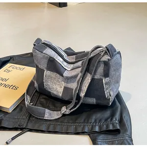 Detailed macro view of washed denim crossbody bag featuring a classic checkerboard pattern