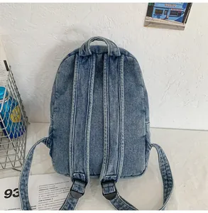 Dettaglio degli spallacci in denim imbottiti e del manico dello zaino blu retrò