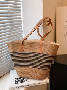 Large straw tote bag with black stripes and brown leather handles for beach vacation