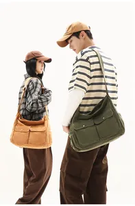 Detail view of large canvas messenger bag with double front pockets and metal buckles