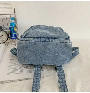 Vista dettagliata del fondo rinforzato e degli spallacci robusti di uno zaino in denim blu