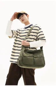 Army green canvas messenger bag worn by a model, featuring double front flap pockets