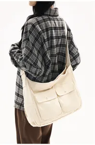 Detailed side view of off-white canvas messenger bag with large double front pockets