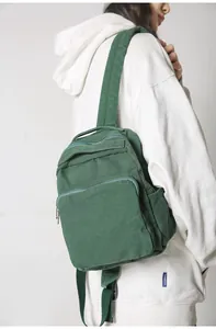 Vista detallada de la mochila de lona verde oscuro con múltiples compartimentos con cremallera