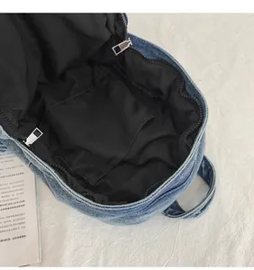 Vista interna dello zaino in denim blu con fodera nera e tasca interna aperta