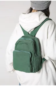 Primer plano de una mochila de lona verde con bolsillos de cremallera en una modelo