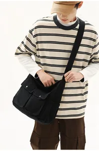 Detailed view of black canvas messenger bag with silver metal buckles and large pockets