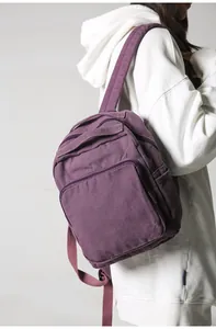Vista lateral de una mochila vintage de lona violeta llevada por modelo con sudadera