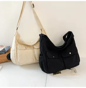 Detail of minimalist canvas messenger bags in beige and black with dual front pockets