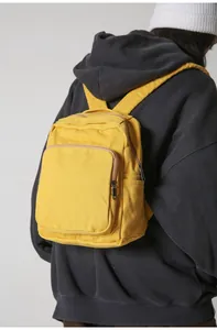 Detalle de una mochila de lona lavada amarillo brillante con bolsillo frontal en modelo