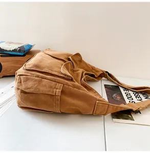 Detail of tan canvas messenger bag featuring dual front pockets and durable wide strap