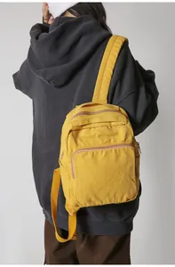 Vista detallada de la mochila de lona amarilla sobre modelo con sudadera gris