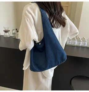 Détail du sac cabas en denim bleu foncé avec large bandoulière et fermoir métallique