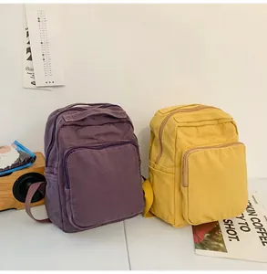 Vista de los detalles de mochilas de lona morada y amarilla con bolsillos delanteros