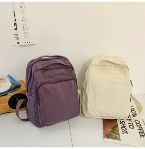 Vista detallada de mochilas de lona vintage en morado y crema con prácticos bolsillos