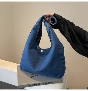 Détail du sac à épaule en jean bleu avec bouton argenté et poignée au design noué