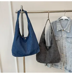 Détail de sacs hobo en denim bleu foncé et gris fumée suspendus à un cintre