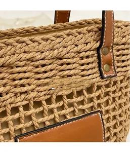 Détail du sac cabas en paille tissée avec poignées en cuir marron et rivets