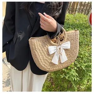 Détail d'un sac en paille avec un nœud en soie blanche et une texture tissée naturelle