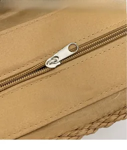 Vue détaillée de la fermeture éclair en métal argenté poli et du tissu tressé du sac