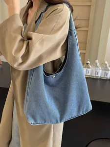 Grand sac cabas en denim bleu délavé avec bouton pression en métal porté à l'épaule